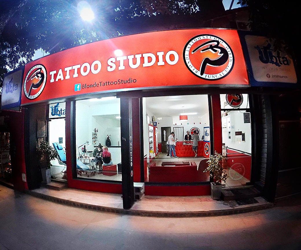 Fachada de Bj Tattoo Studio iluminada de noche en Merlo